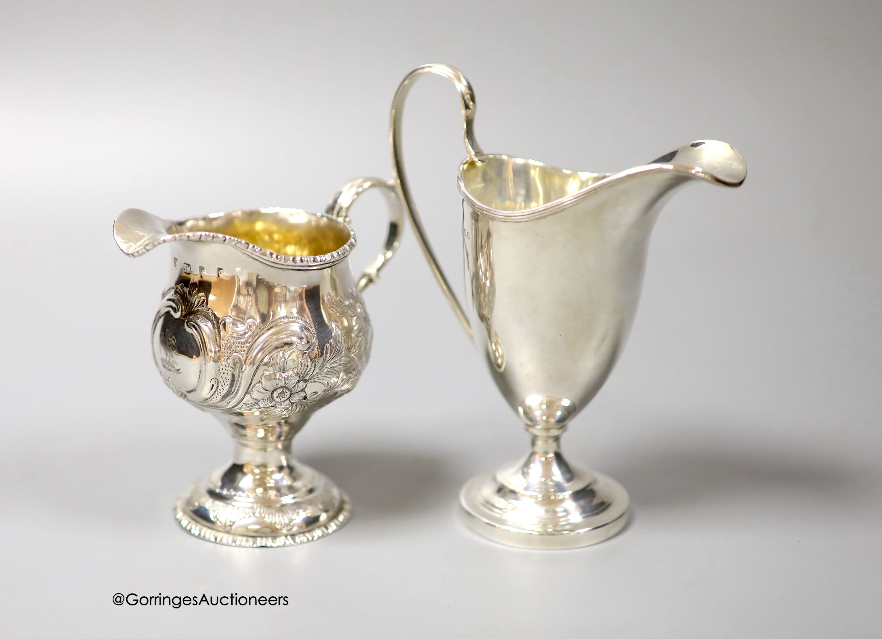 A George III silver inverted pear shaped cream jug, with later embossed decoration, marks rubbed, 9.7cm and a later cream jug, gross 210 grams.